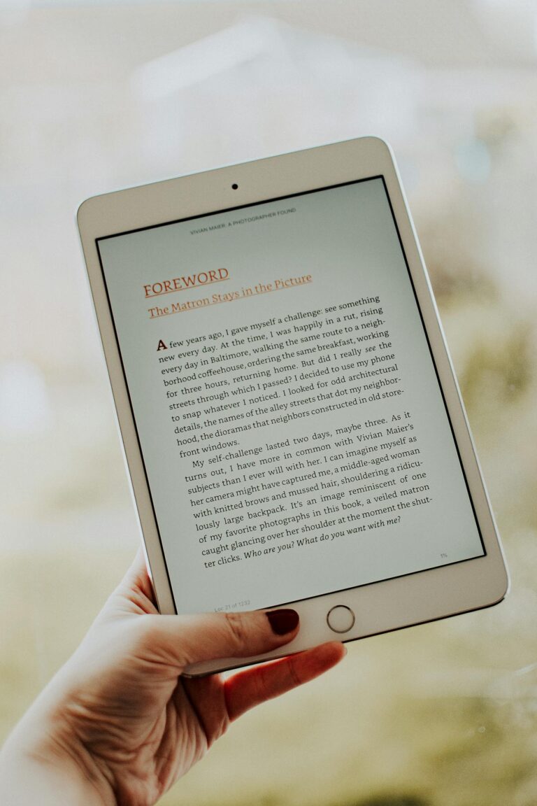 Close-up of a hand holding a tablet displaying an e-book page.