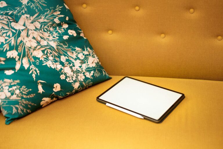 Stylish tablet on a mustard sofa with a floral cushion, ideal for tech and home decor concepts.