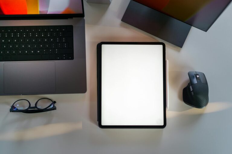 Top view of a digital workspace with a laptop, blank tablet, and mouse on a desk.